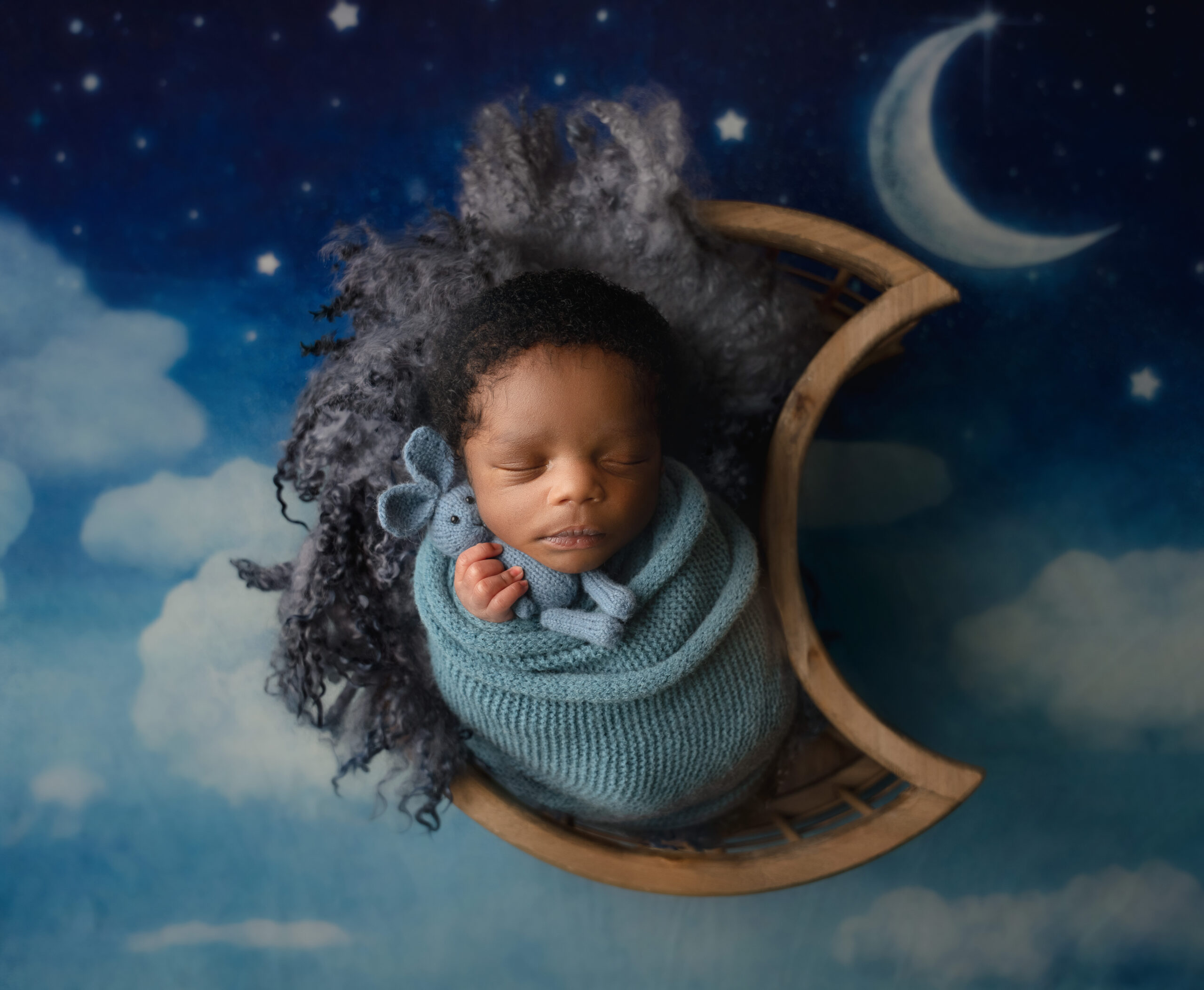 baby boy posed in moon basket on starry night sky backdrop during session with Raleigh Newborn Photographer
