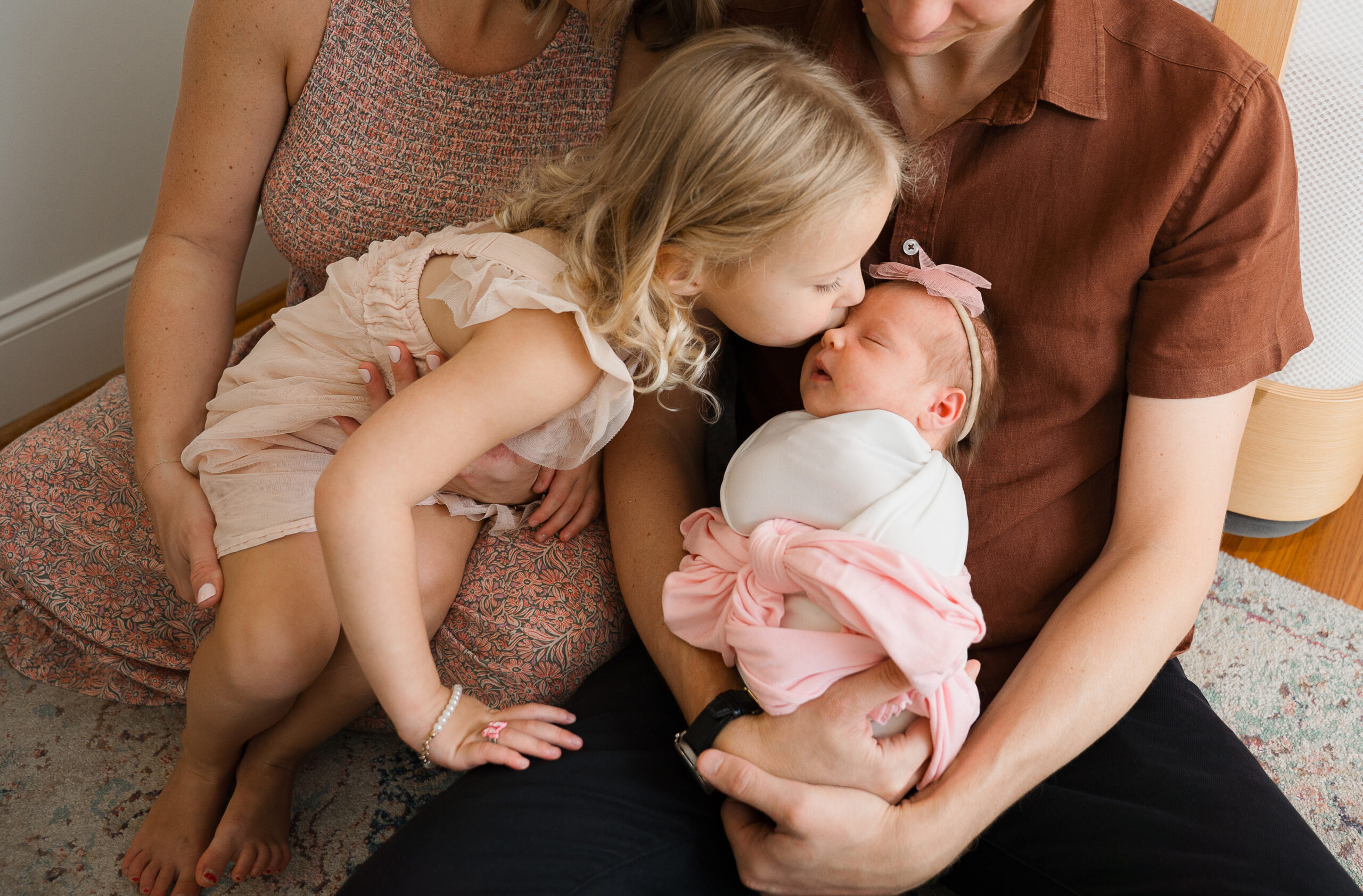 big sister kissing her newborn baby sister on the cheek during session with raleigh newborn photographer