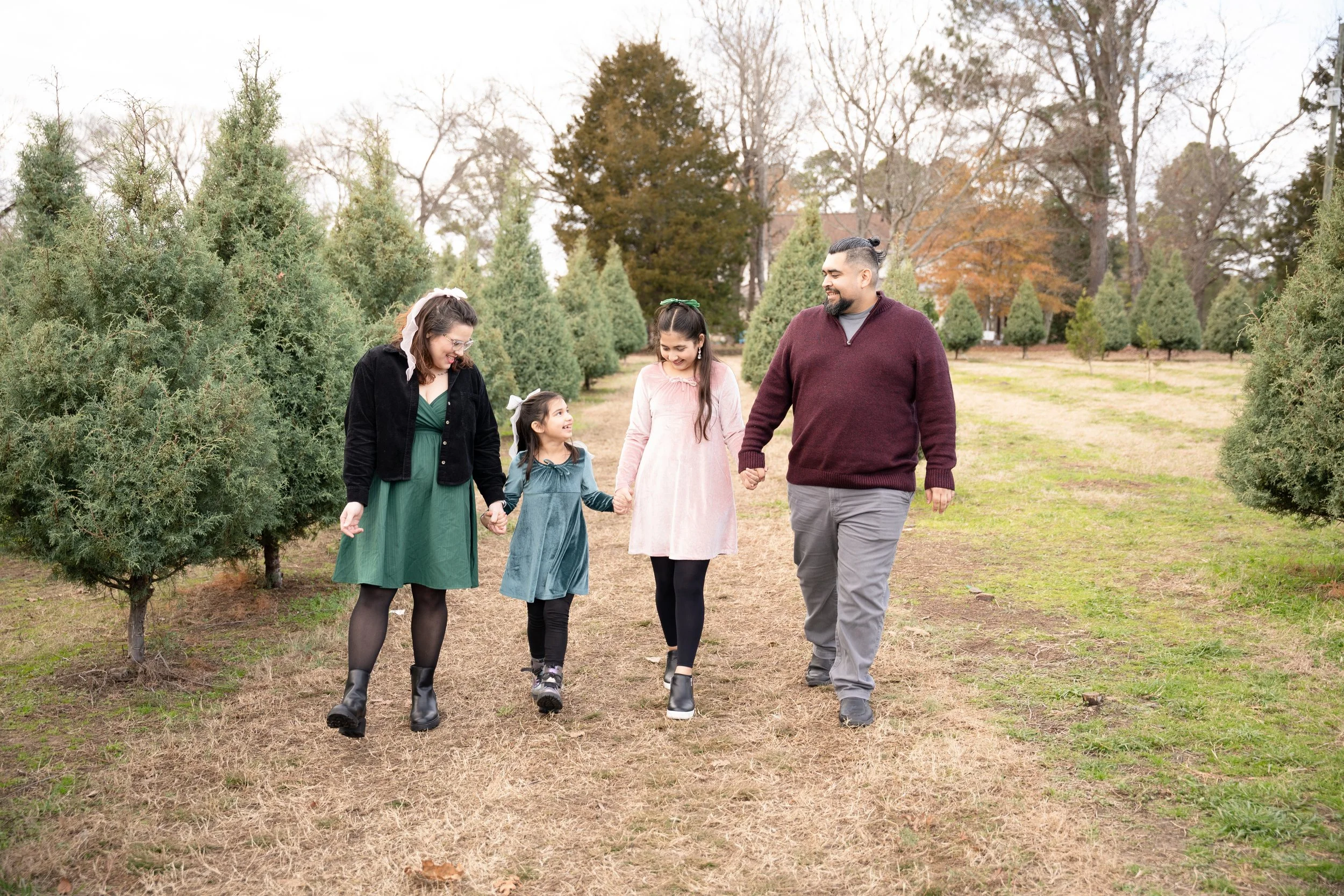 family of 4 walking through a christmas tree farm during session with raleigh family photographer5